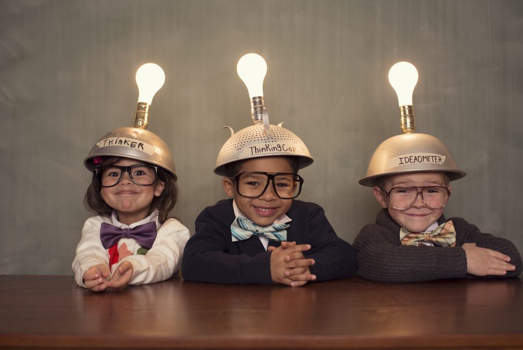 Tres niños caracterizados de inventores con cascos de bombillas