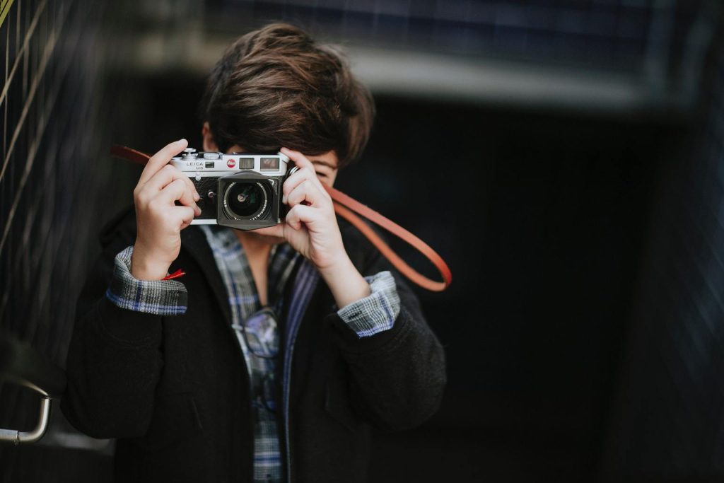 joven fotografiando con cámara analógica en exterior