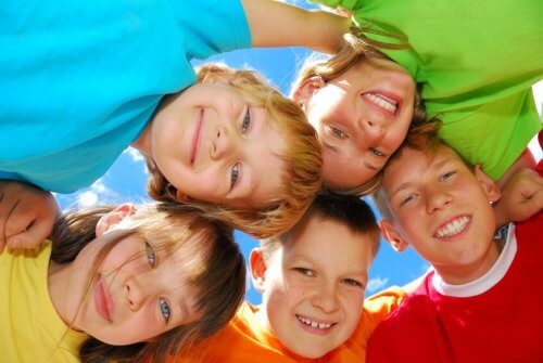 grupo de niños sonrientes unidos en círculo al aire libre