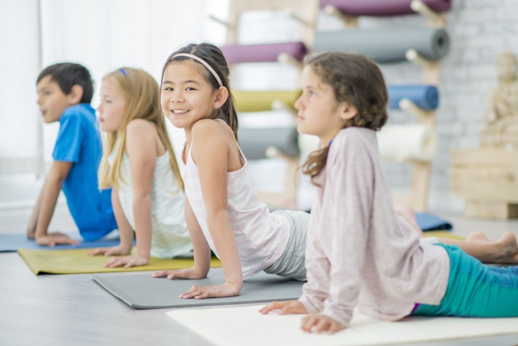 niñas practicando posturas de yoga sobre esterillas