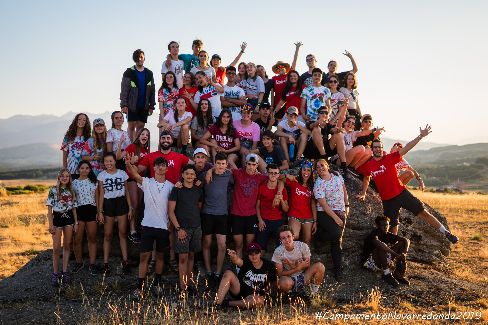 grupo numeroso de jóvenes posando en colina al atardecer