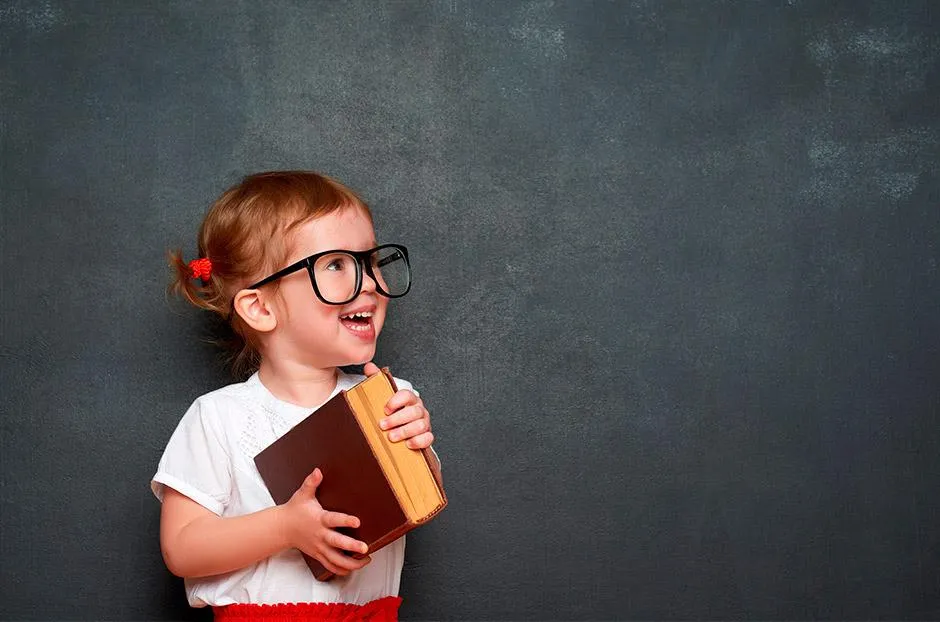 niña pequeña con gafas sosteniendo un libro