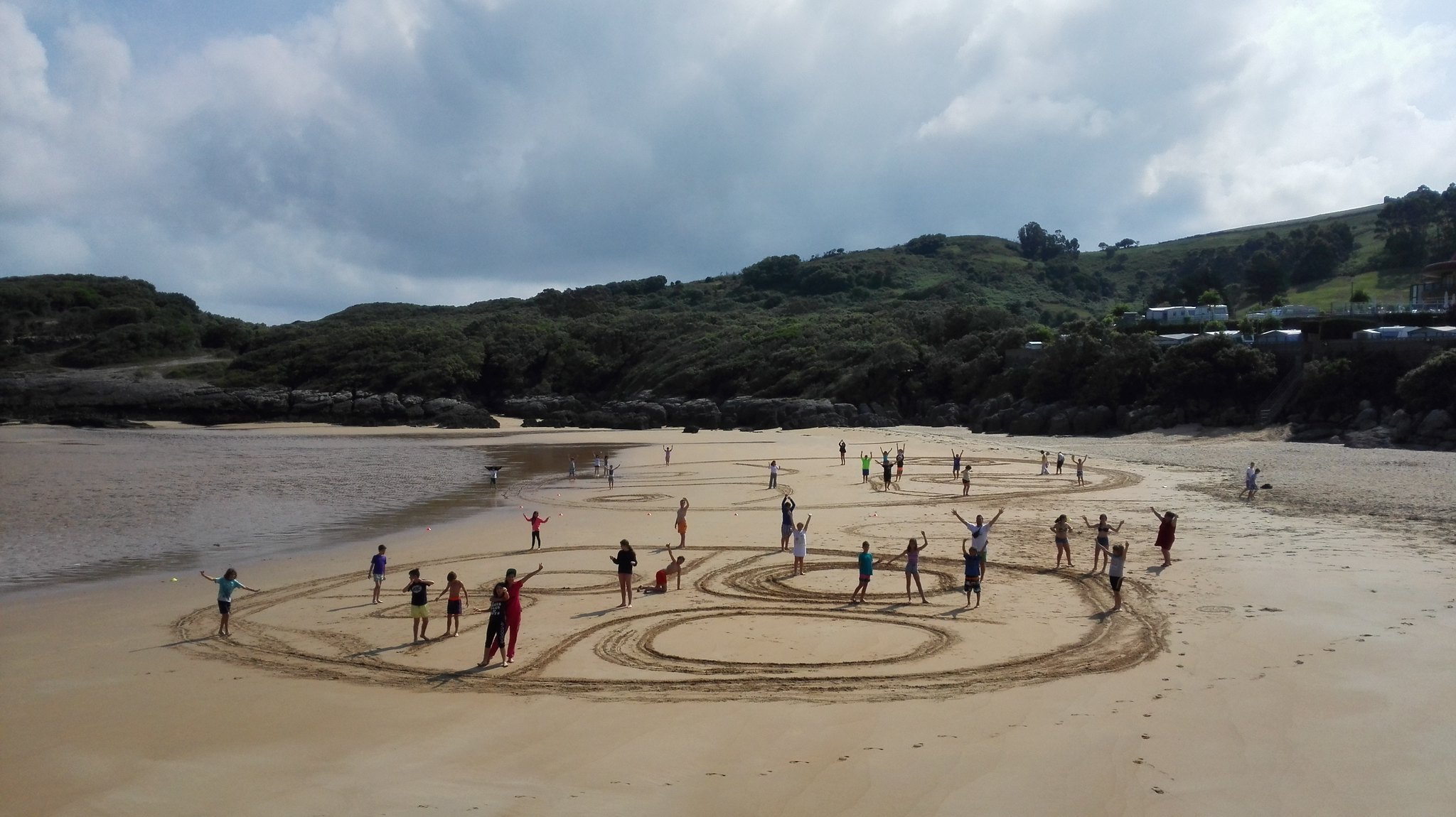 niños dibujando figuras en la arena de la playa