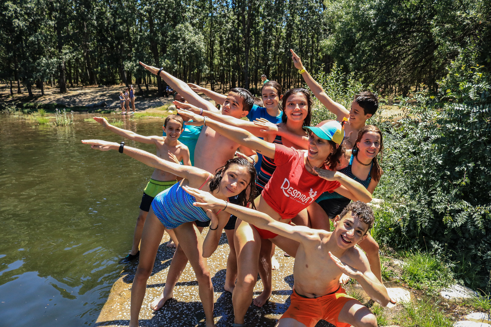 monitora y niños posando divertidos junto a río en verano