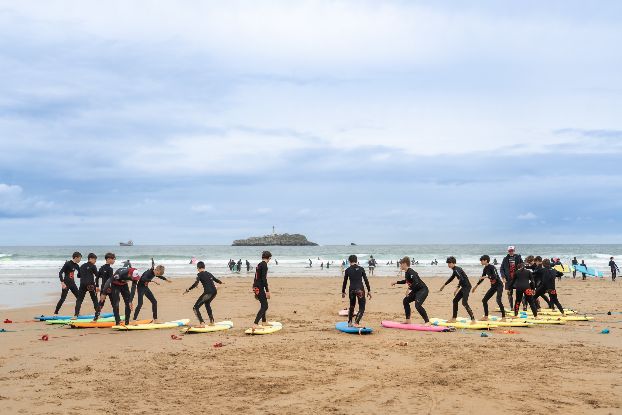 jóvenes practicando surf en fila sobre la arena
