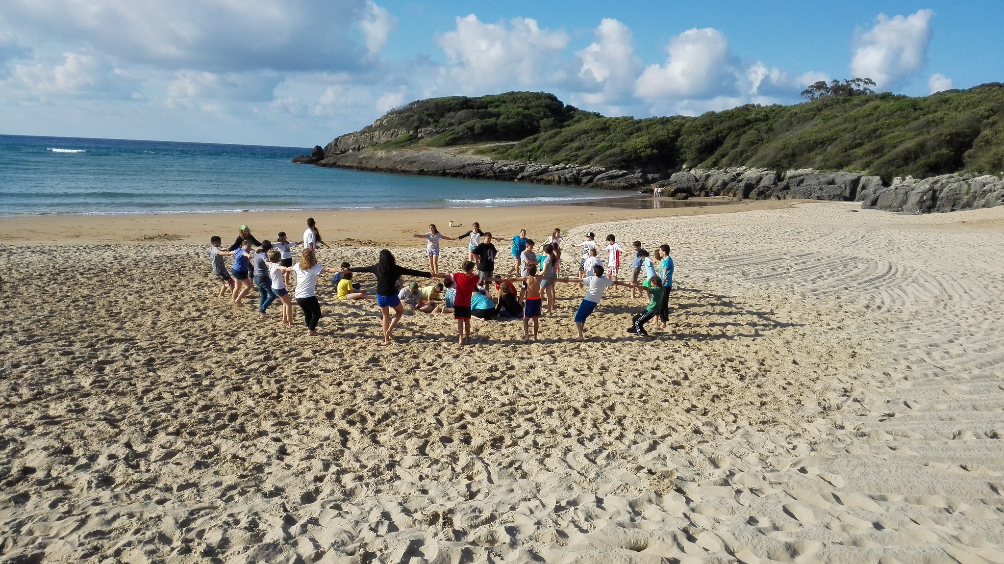 niños cogidos de la mano en círculo en la playa