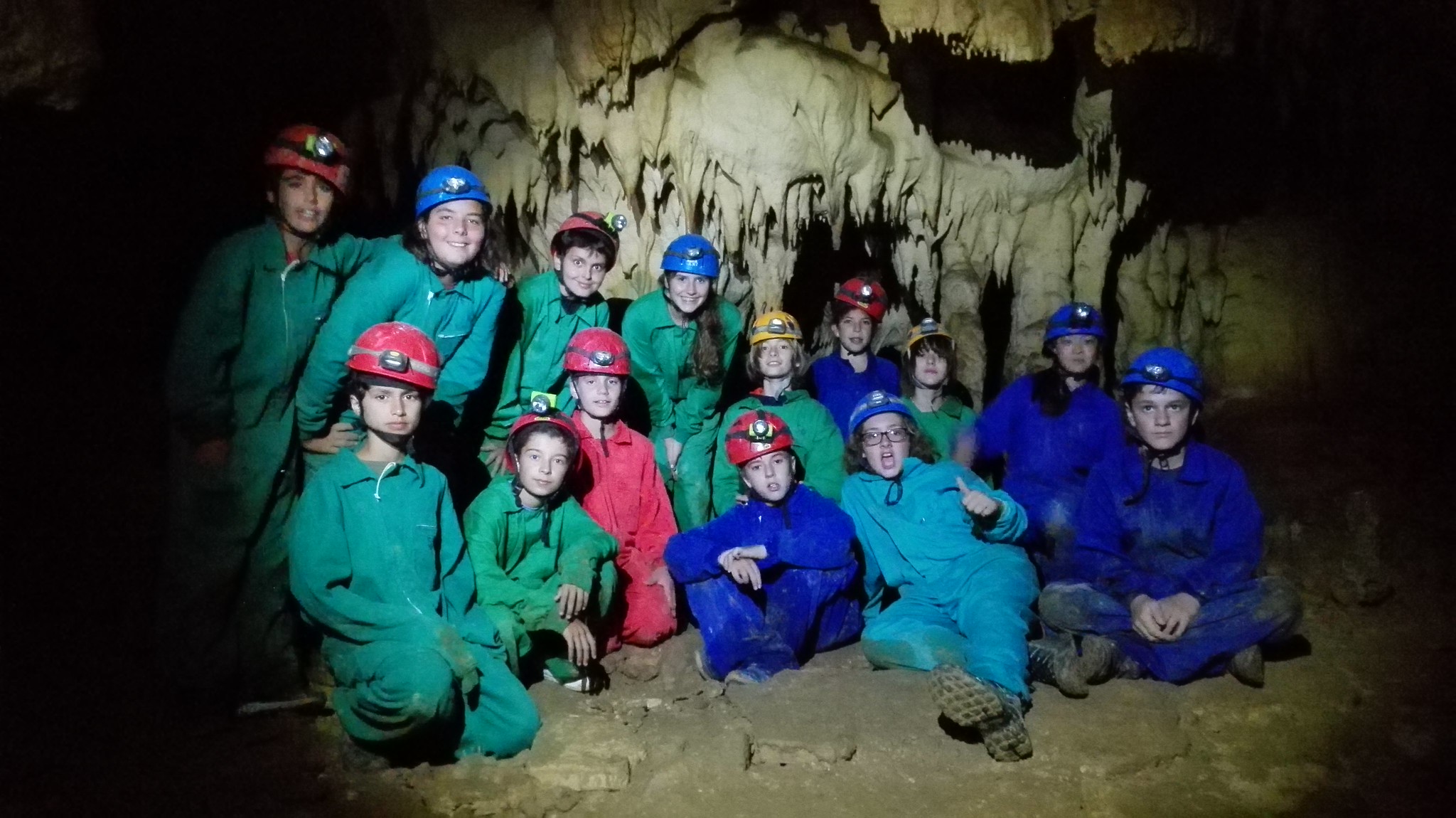 grupo de niños en cueva con monos y cascos de espeleología