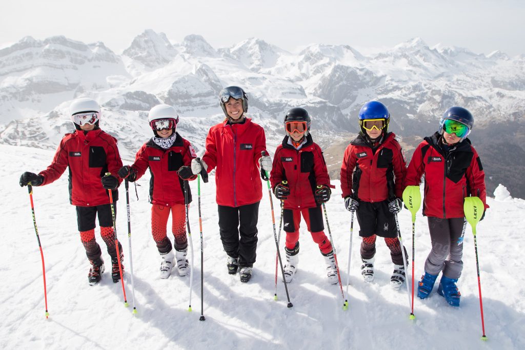 grupo de niños esquiadores posando en la nieve con montañas