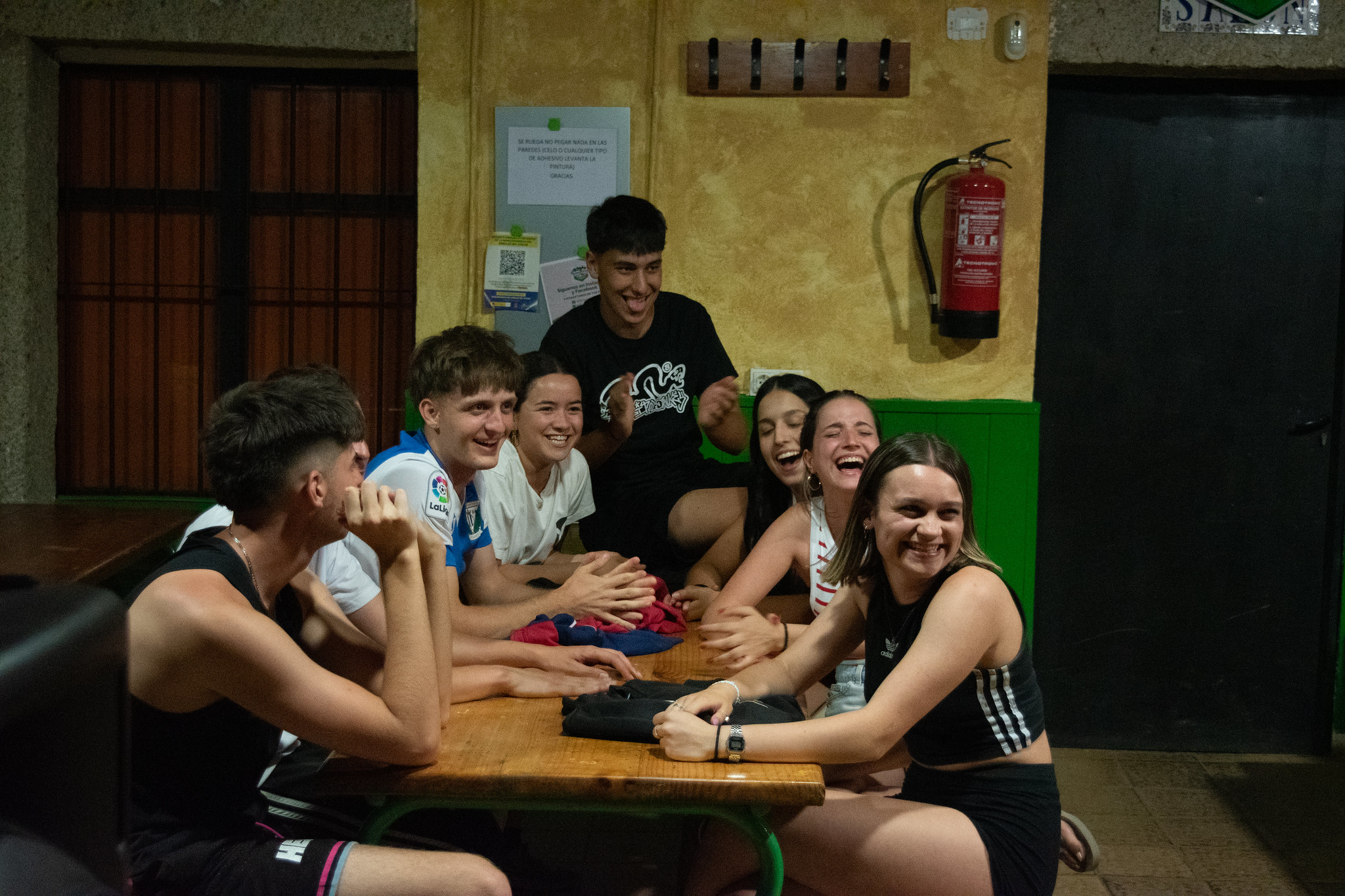grupo de jóvenes riendo juntos en mesa de campamento
