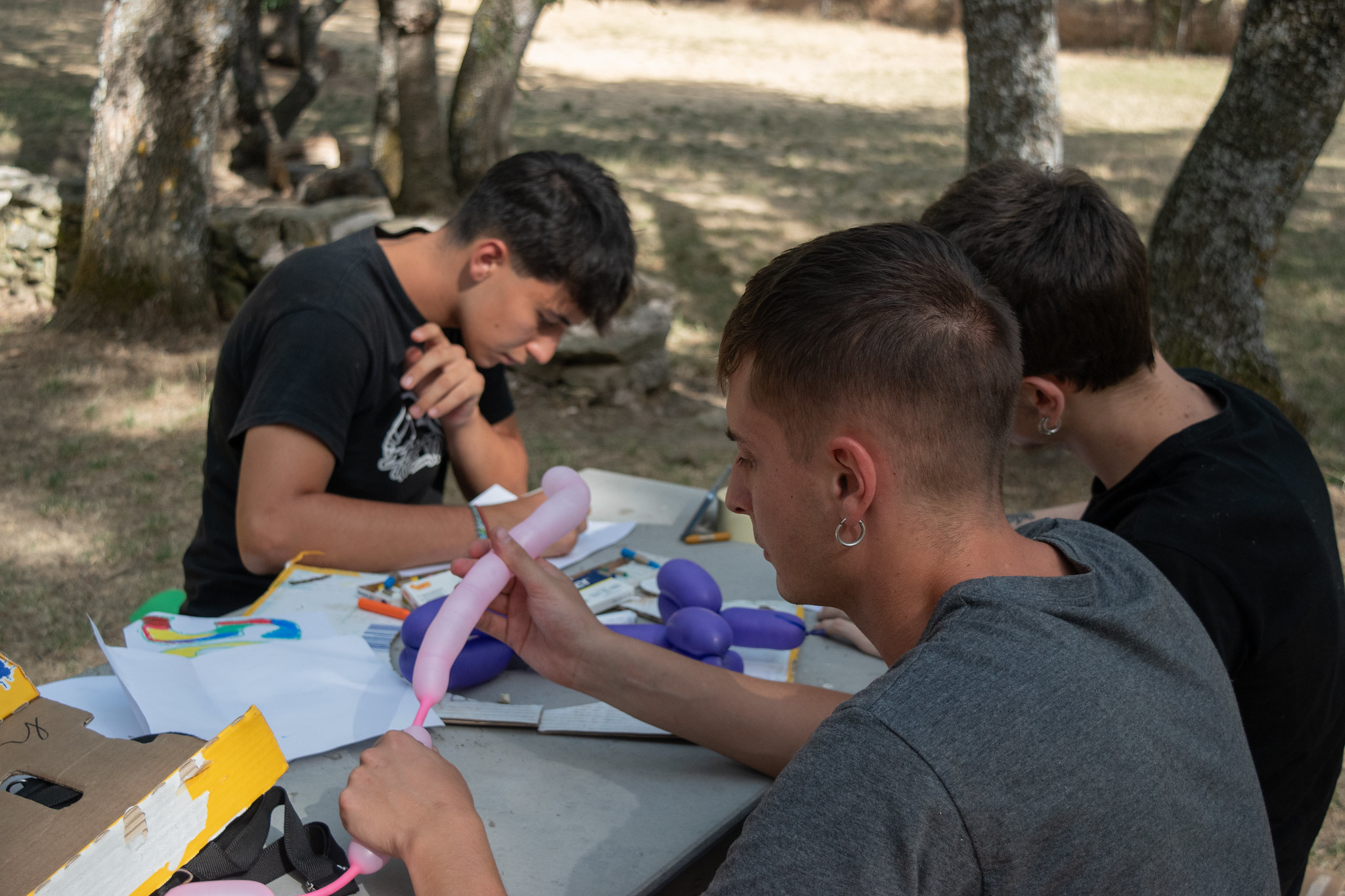 jóvenes haciendo manualidades al aire libre en mesas