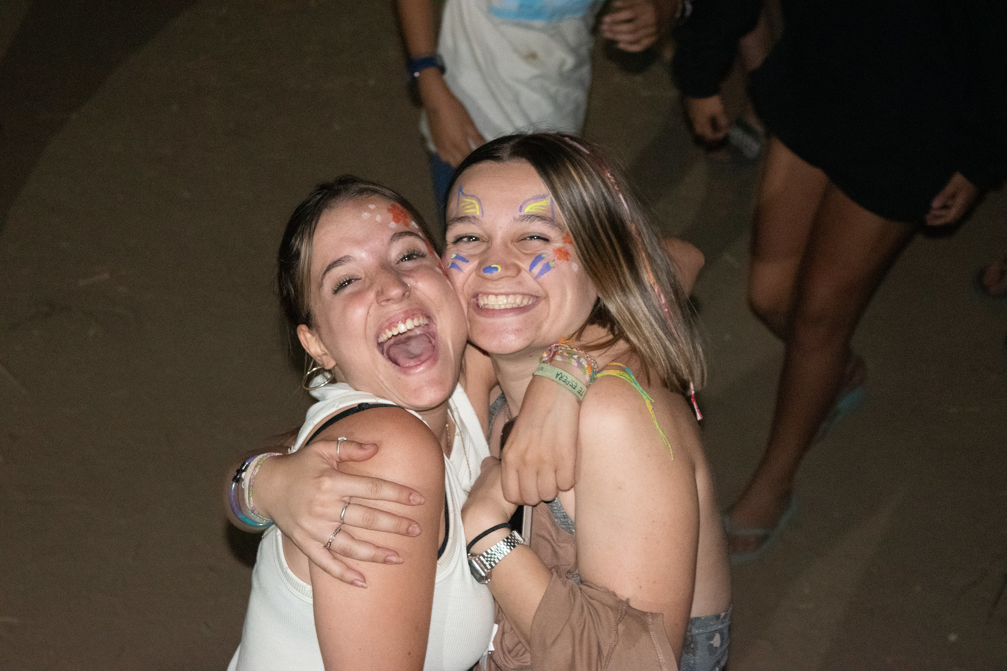 dos chicas abrazadas riendo de noche en campamento