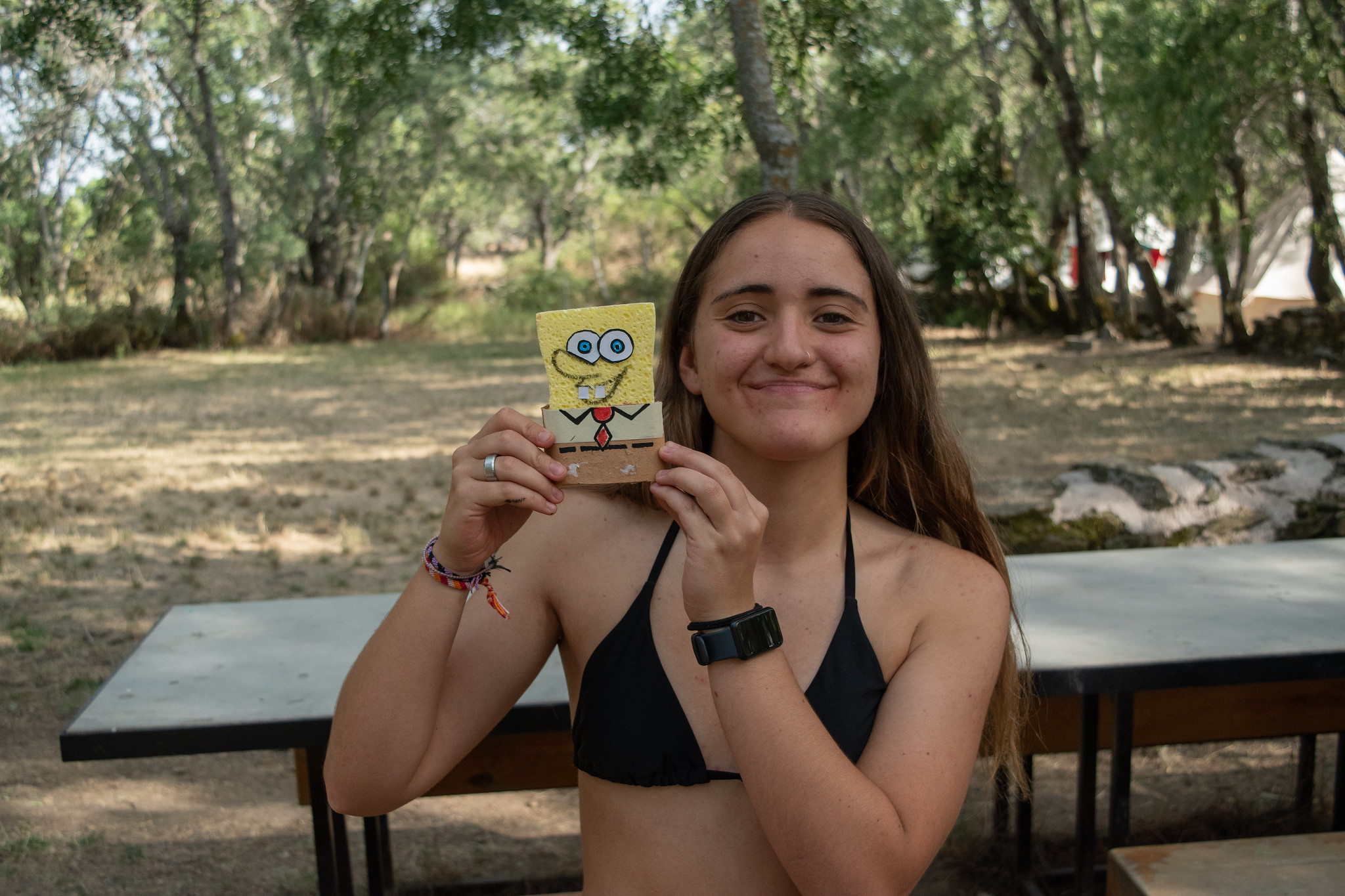 chica sonriendo con figura de bob esponja en campamento