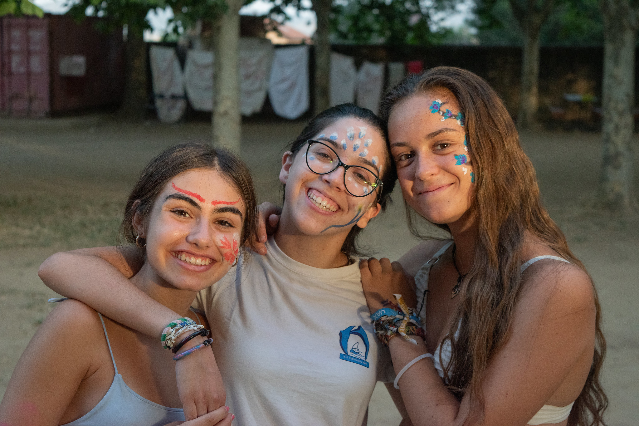 tres chicas con pintura facial sonriendo en campamento