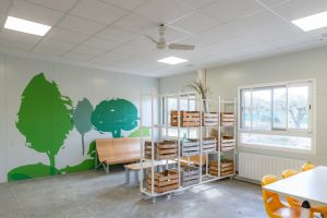 sala de actividades con mural de árboles y estanterías