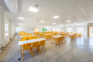 comedor amplio con mesas y sillas amarillas en albergue