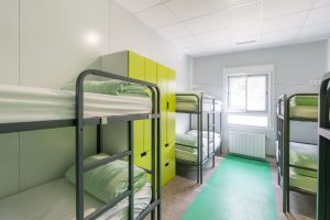 habitación con literas verdes y armarios en albergue