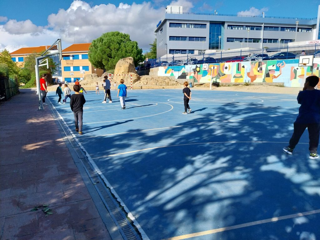 niños practicando deporte en pista azul exterior con murales