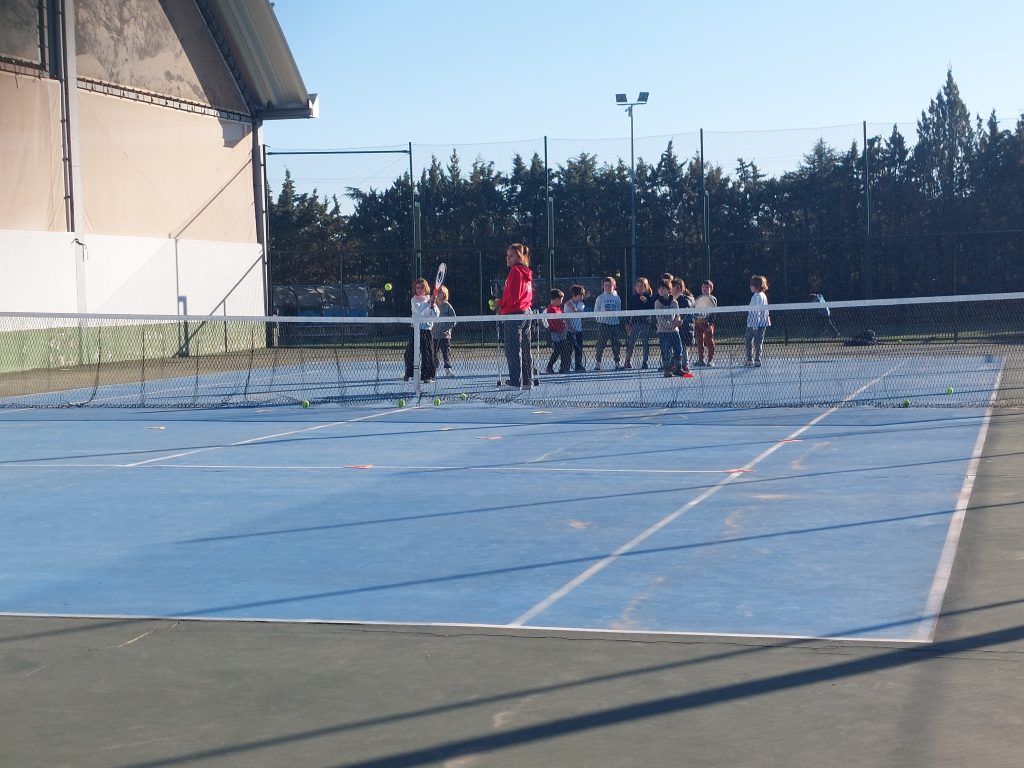 niños en clase de tenis en pista al aire libre