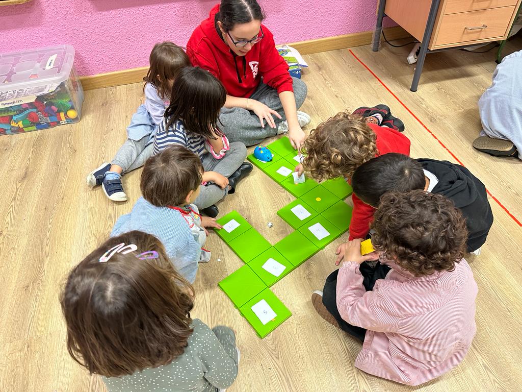 monitora y niños jugando con bloques de colores en el suelo
