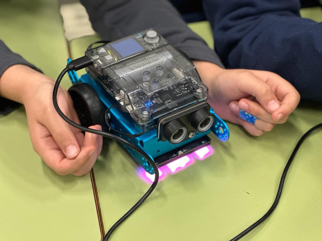 niño manipulando robot programable en actividad de robótica