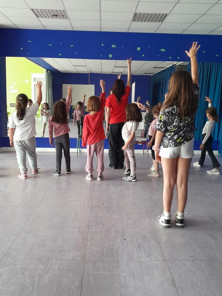 niñas con brazos levantados en clase de baile moderno