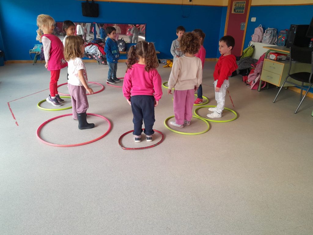niñas haciendo ejercicio con aros de colores en gimnasio