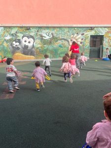 niños corriendo en patio con mural de animales al fondo