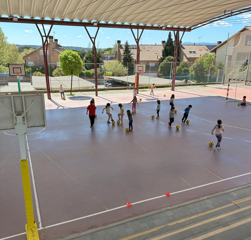niños jugando al fútbol en pista cubierta exterior