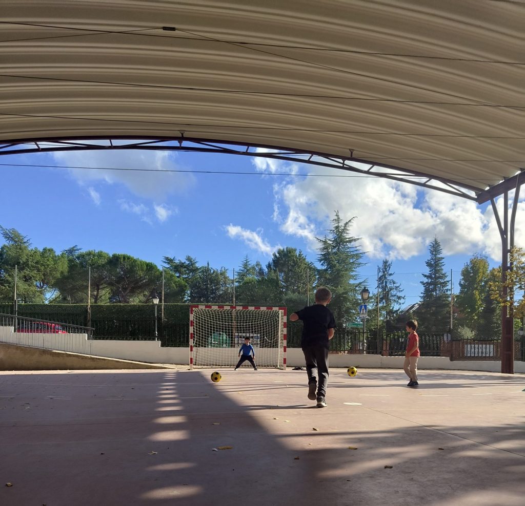 niños jugando al fútbol en pista cubierta con porterías