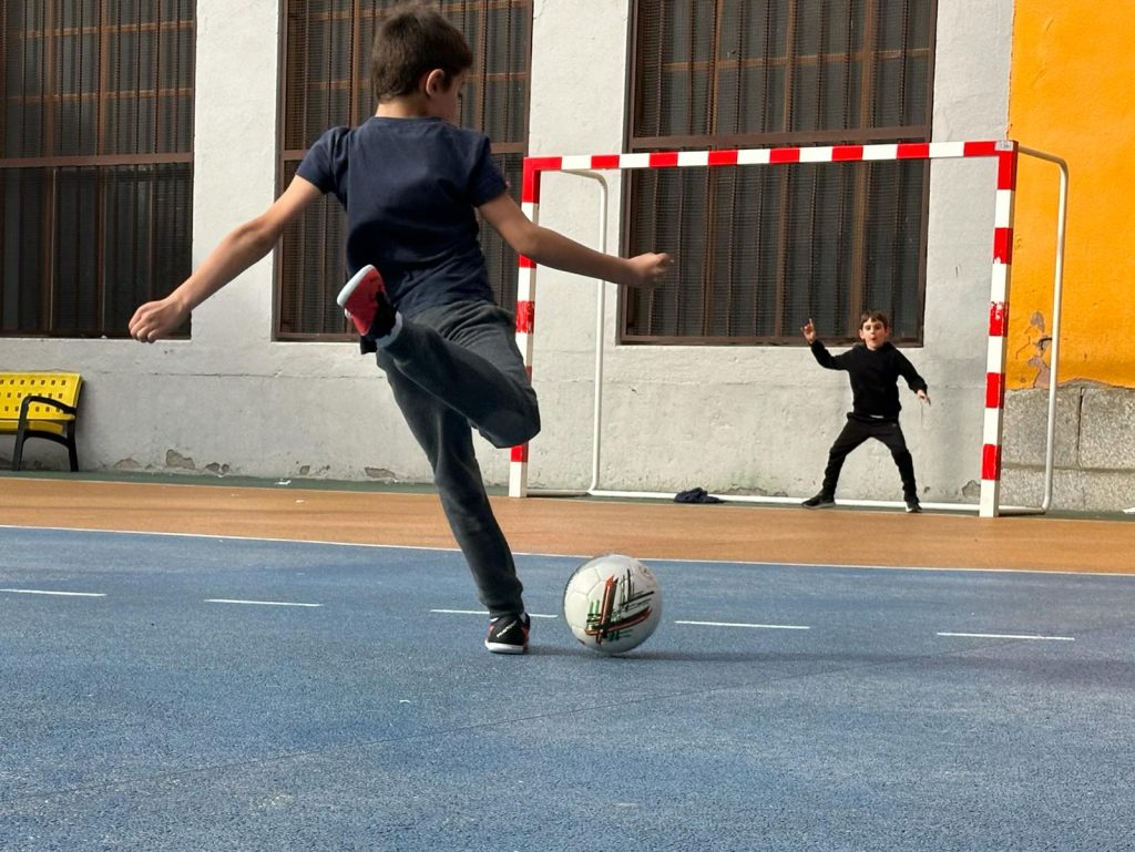 niño chutando un balón de fútbol hacia la portería