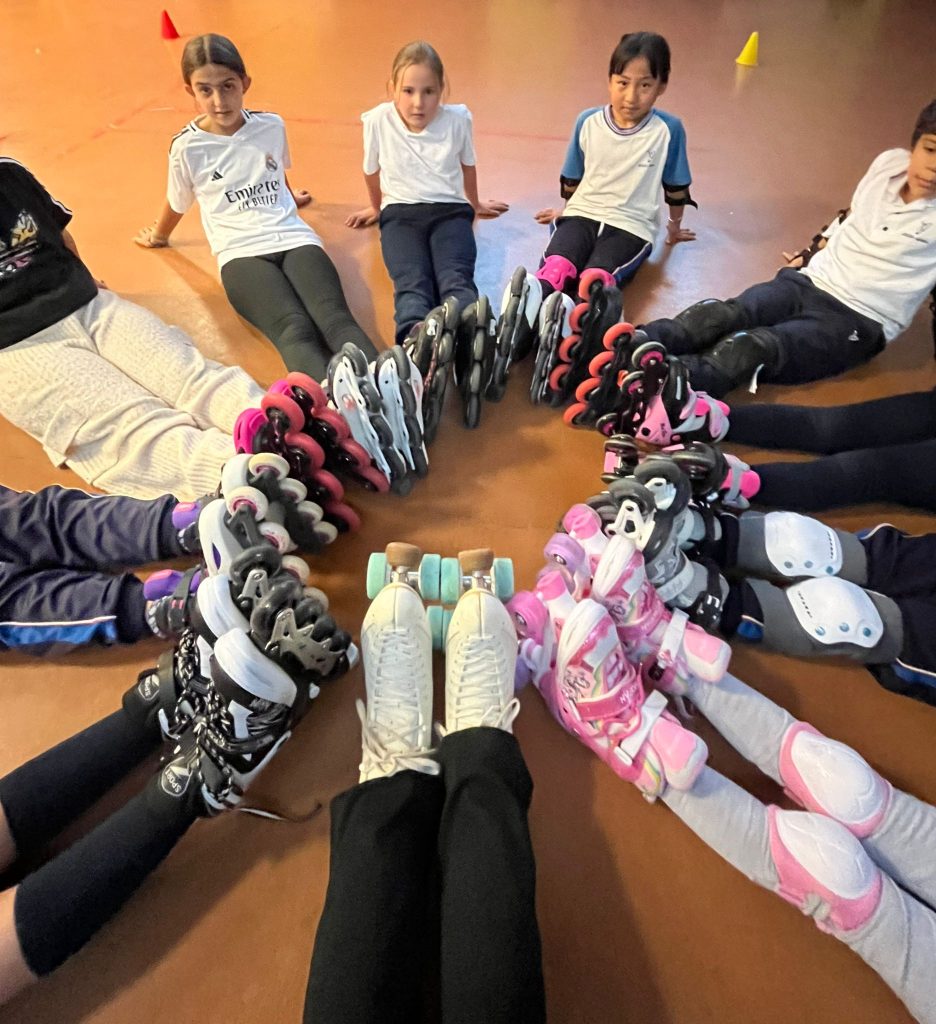niñas sentadas en círculo con patines en el suelo