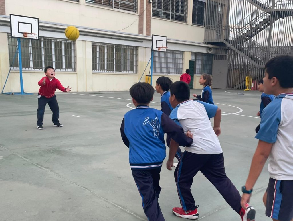 niños jugando al balón en patio exterior del colegio