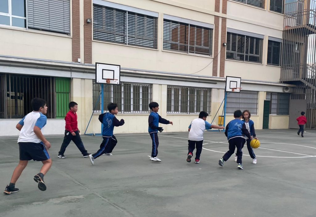 niños jugando al balón en pista deportiva del colegio
