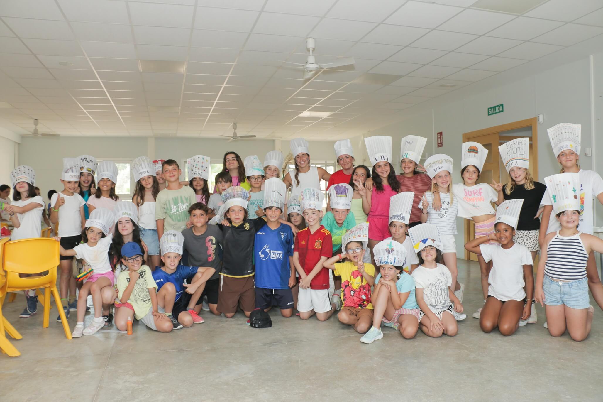 grupo de niños con gorros de cocinero en taller de cocina