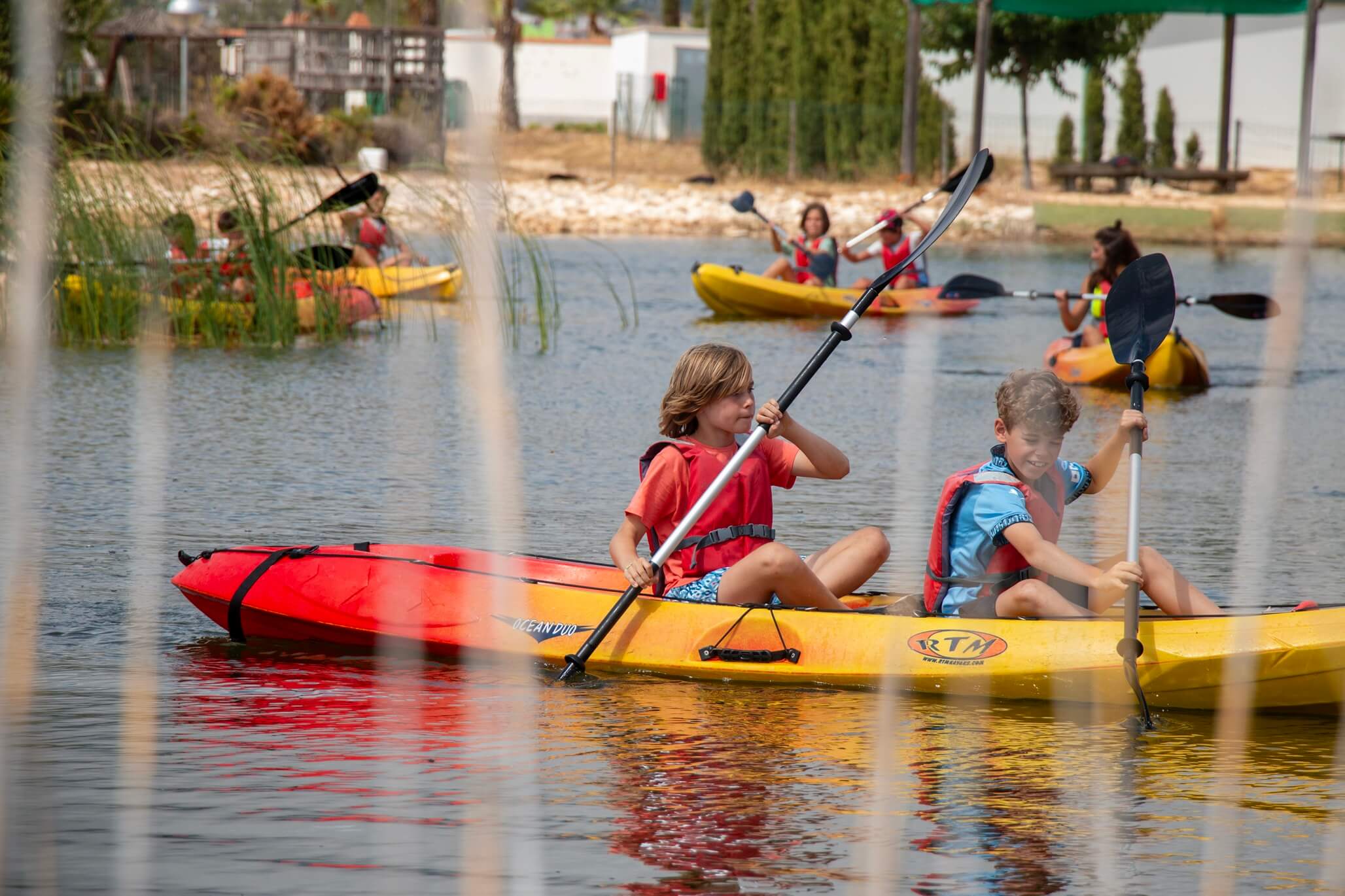 niños haciendo kayak en lago durante campamento de verano