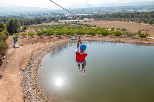 niño en tirolina sobre lago en instalación de campamento