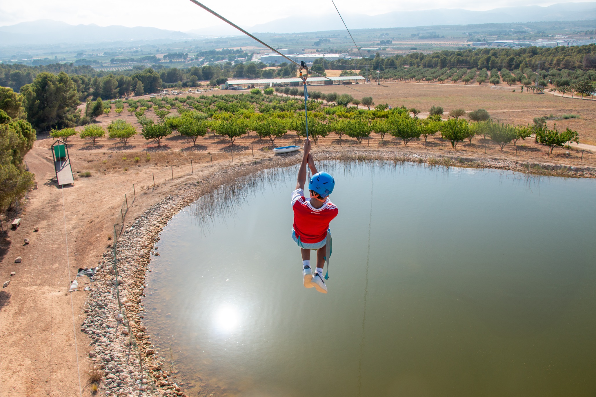 niño en tirolina sobre lago en instalación de campamento