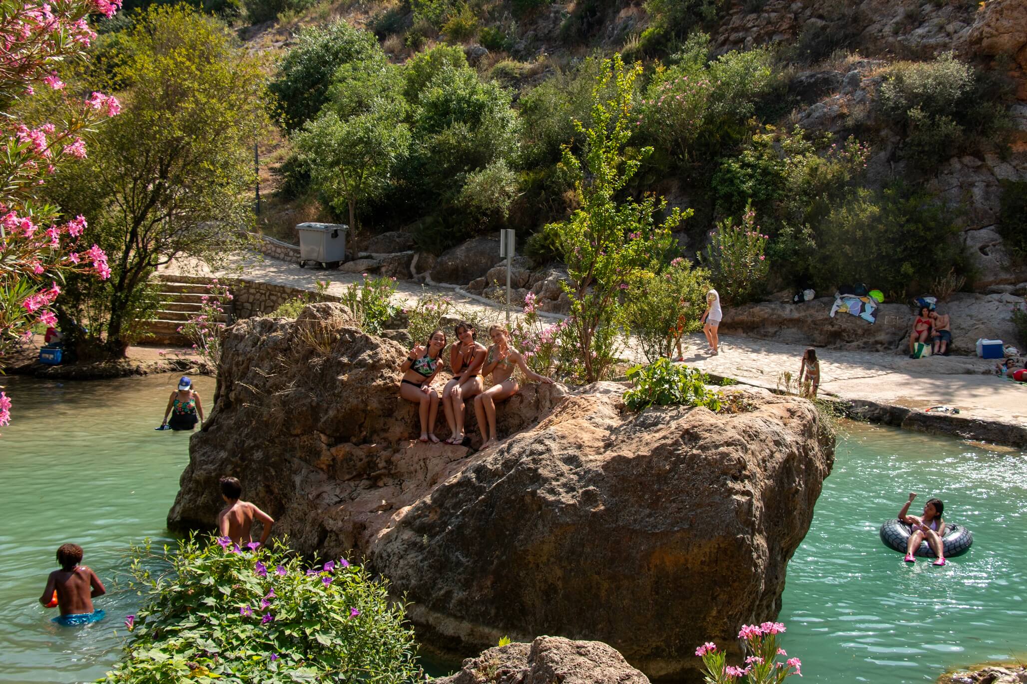 niños bañándose en río natural entre rocas y vegetación