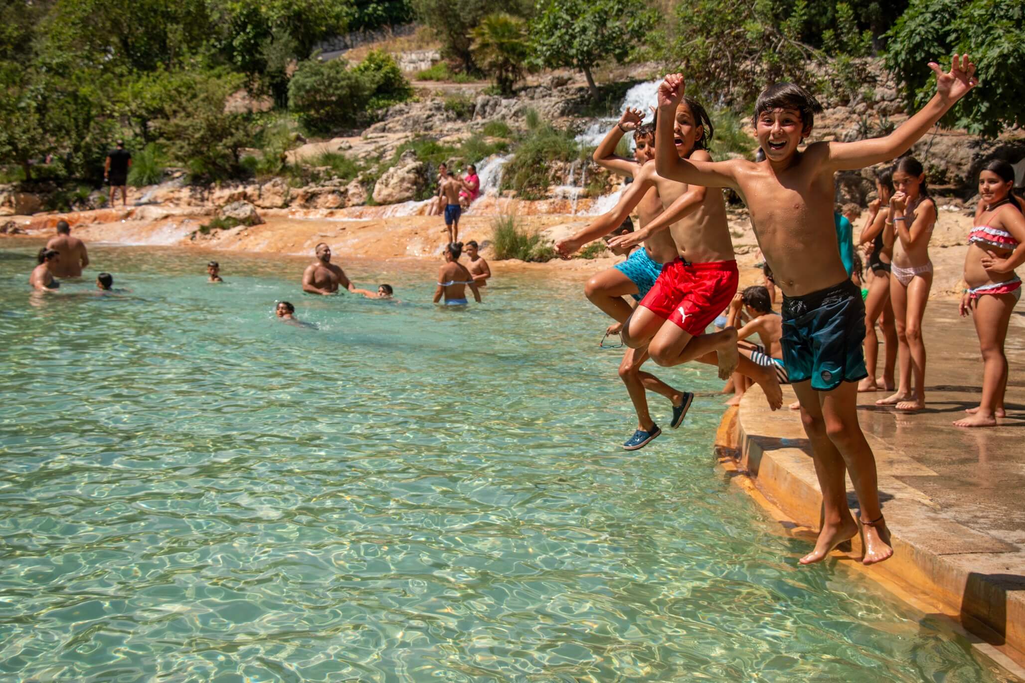 dos niños saltando juntos al agua en río natural
