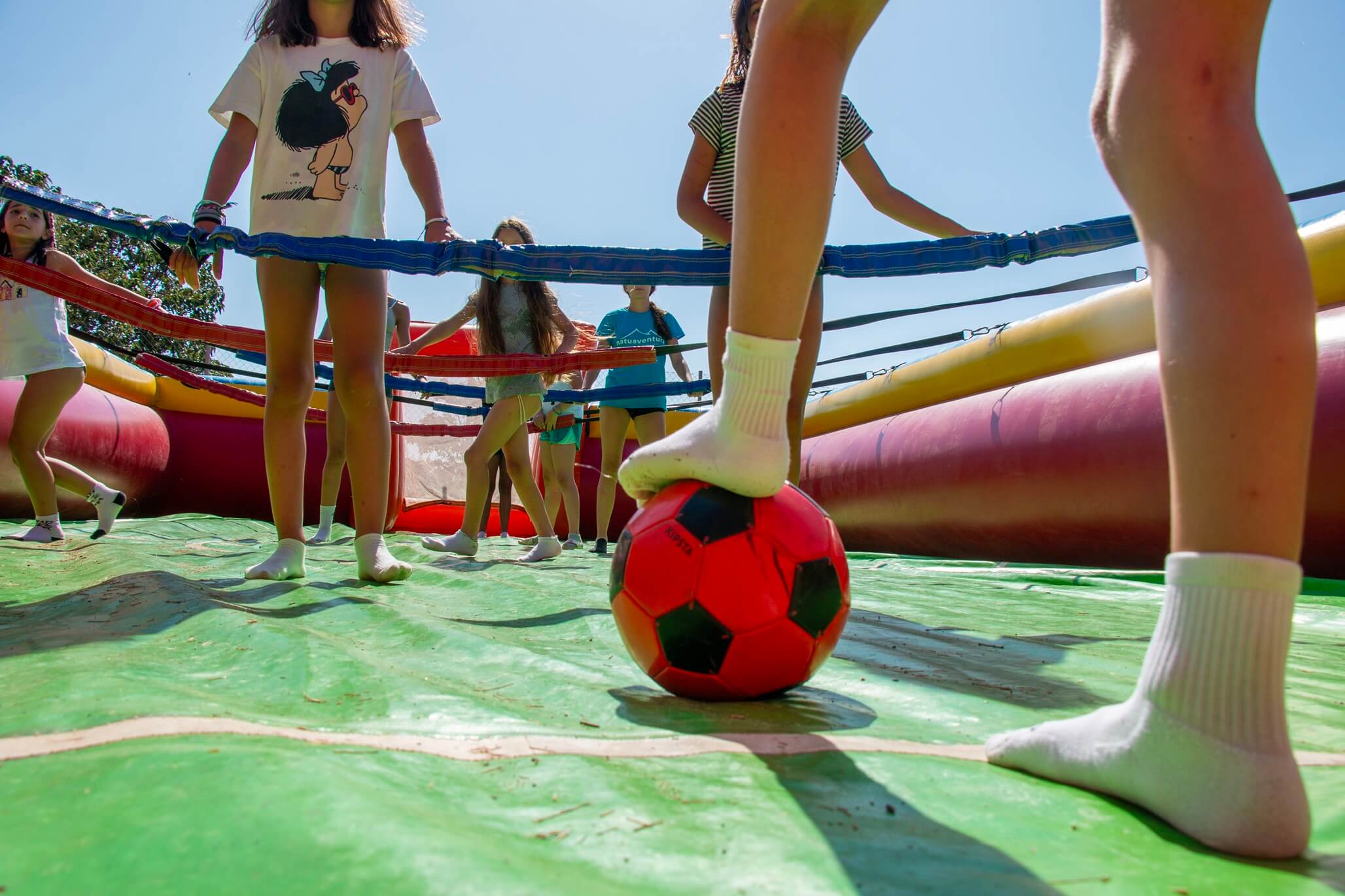 niños jugando al fútbol en hinchable durante campamento