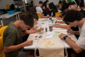 jóvenes pintando bolsas de tela en taller de manualidades